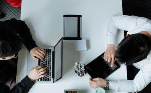 Dos personas sentadas una en frente de la otra con diferentes dispositivos