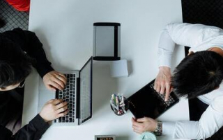 Dos personas sentadas una en frente de la otra con diferentes dispositivos