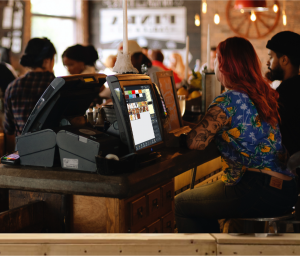 Camarera en la barra del bar junto al monitor y el software de IMM Pos